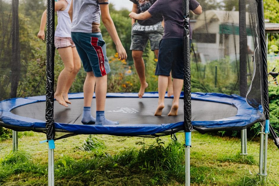 Vaikai šokinėja ant lauko batuto saugiai įrengtoje ir prižiūrimoje žaidimų aikštelėje